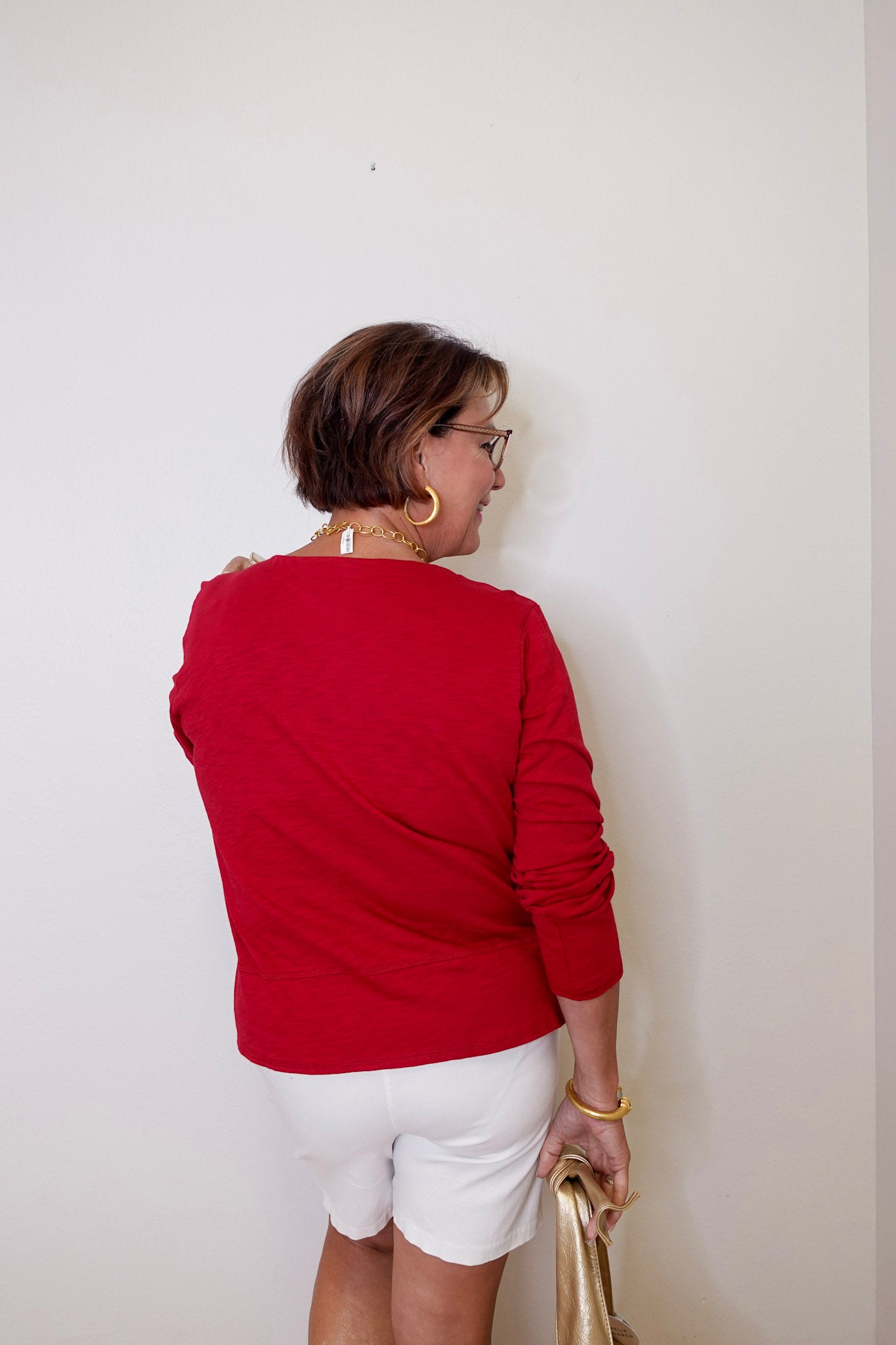 Person wearing a red top and white shorts against a plain background