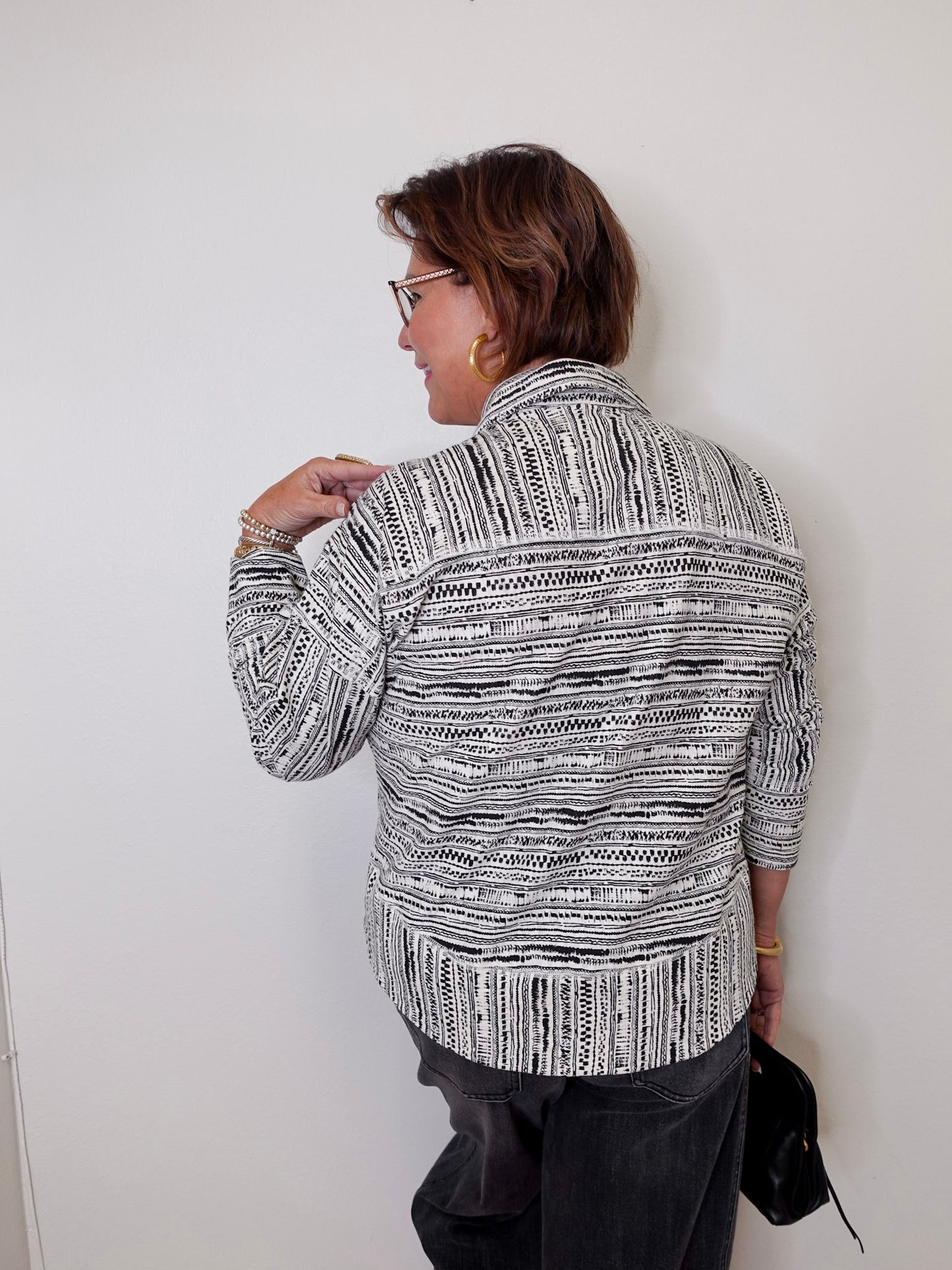 Woman wearing a patterned jacket against a white wall