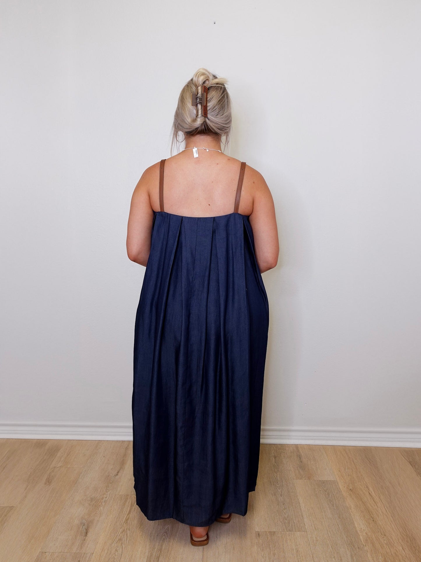 Person wearing a navy blue dress standing against a white wall.