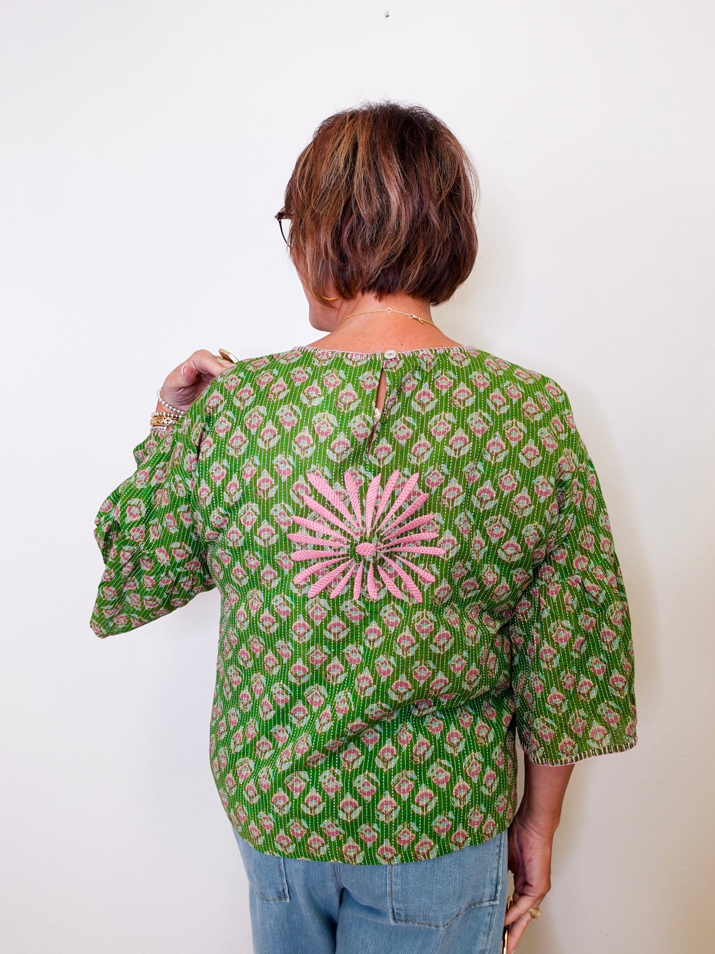 Person wearing a green patterned blouse with a white background