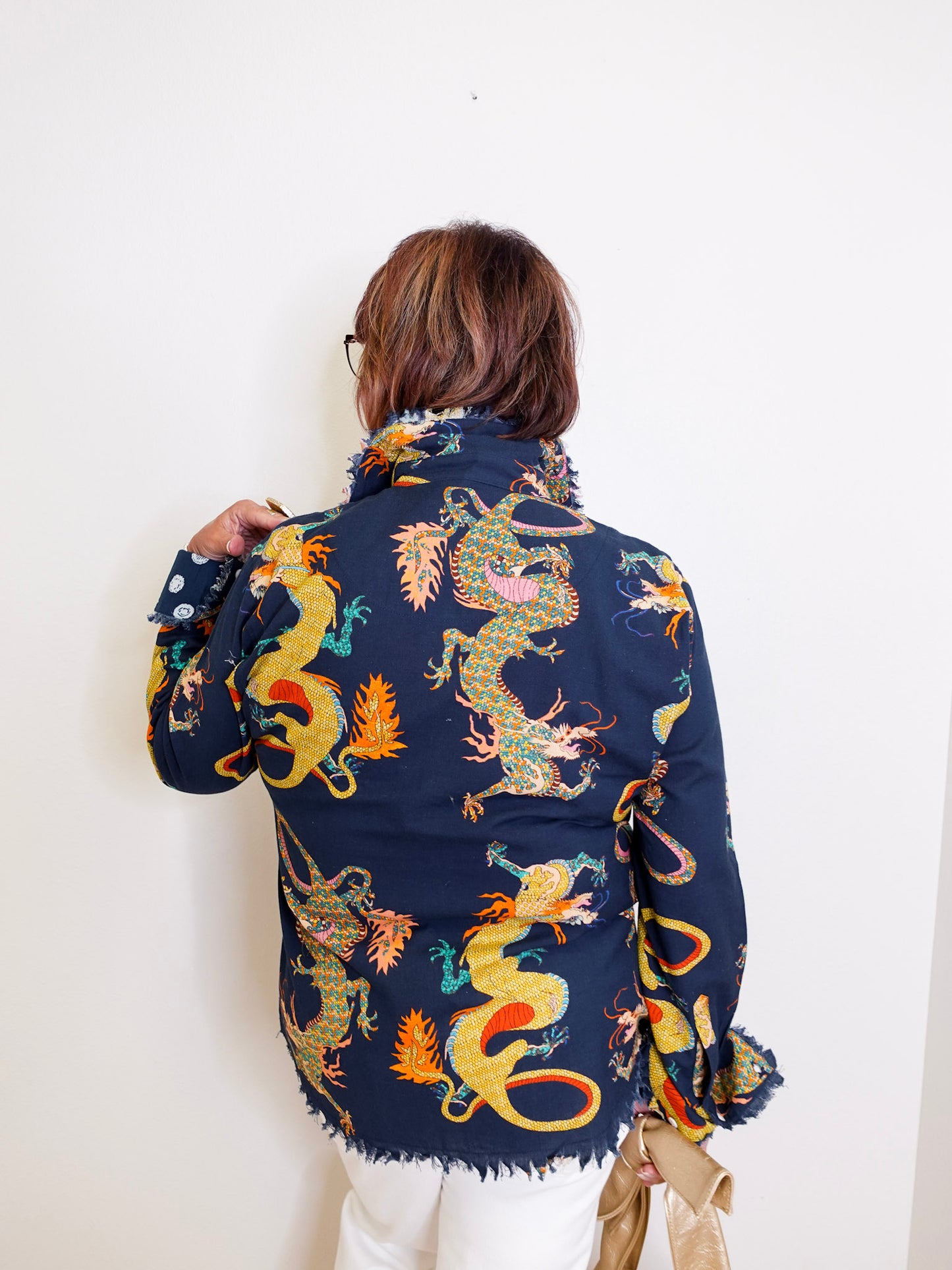 Person wearing a navy blue jacket with colorful dragon patterns against a white background
