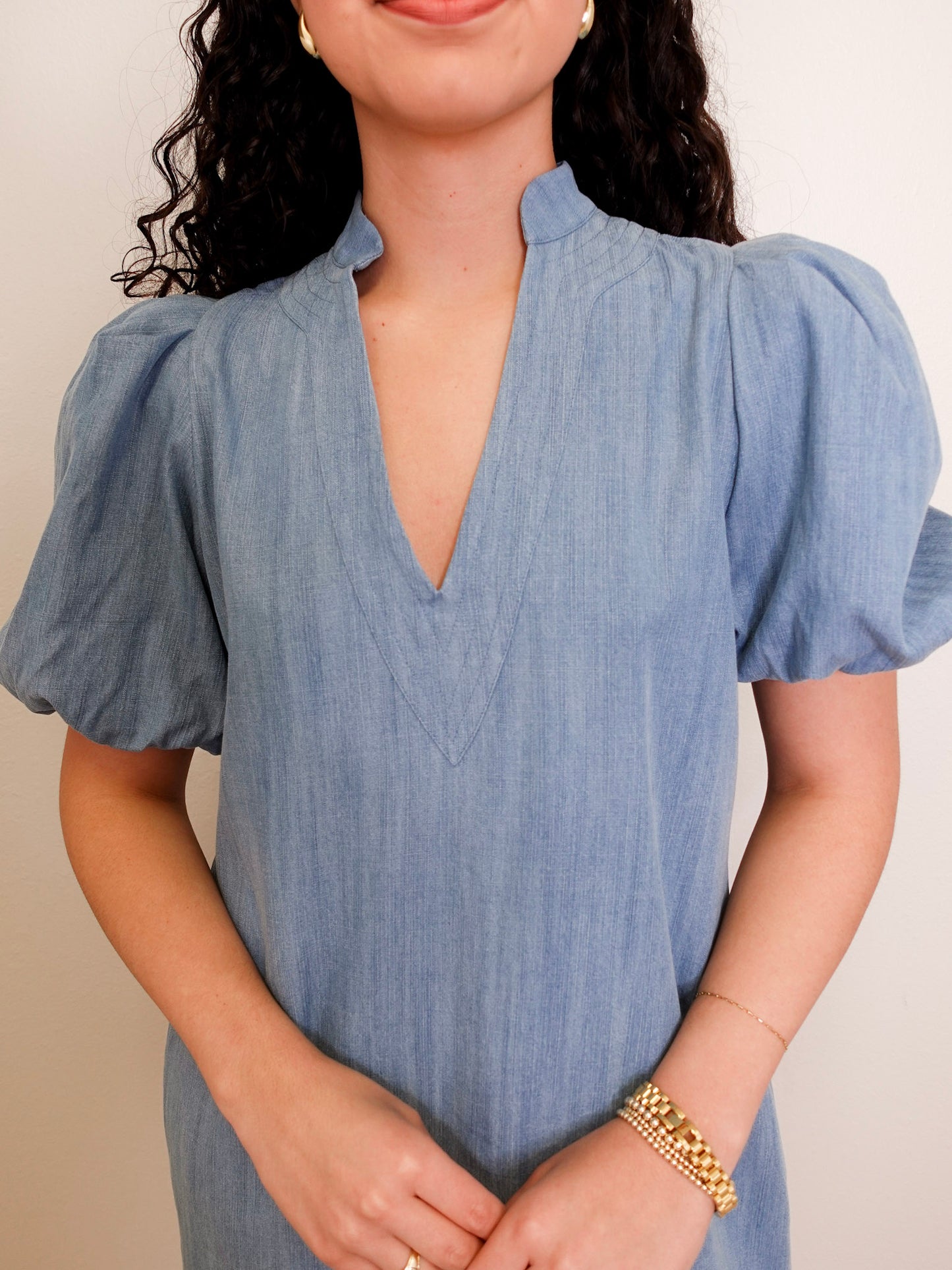 Woman wearing a blue dress with puffed sleeves against a neutral background