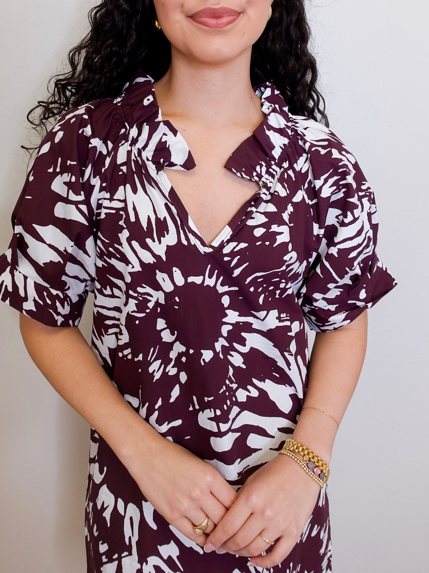 Woman wearing a maroon and white patterned dress against a plain background