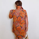 Woman wearing a patterned dress against a white wall