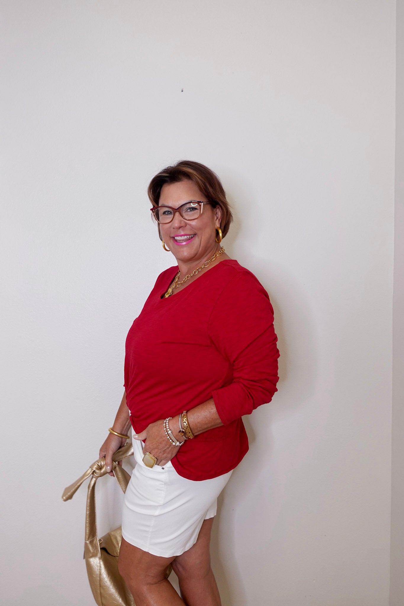 Woman wearing a red top and white shorts against a plain background