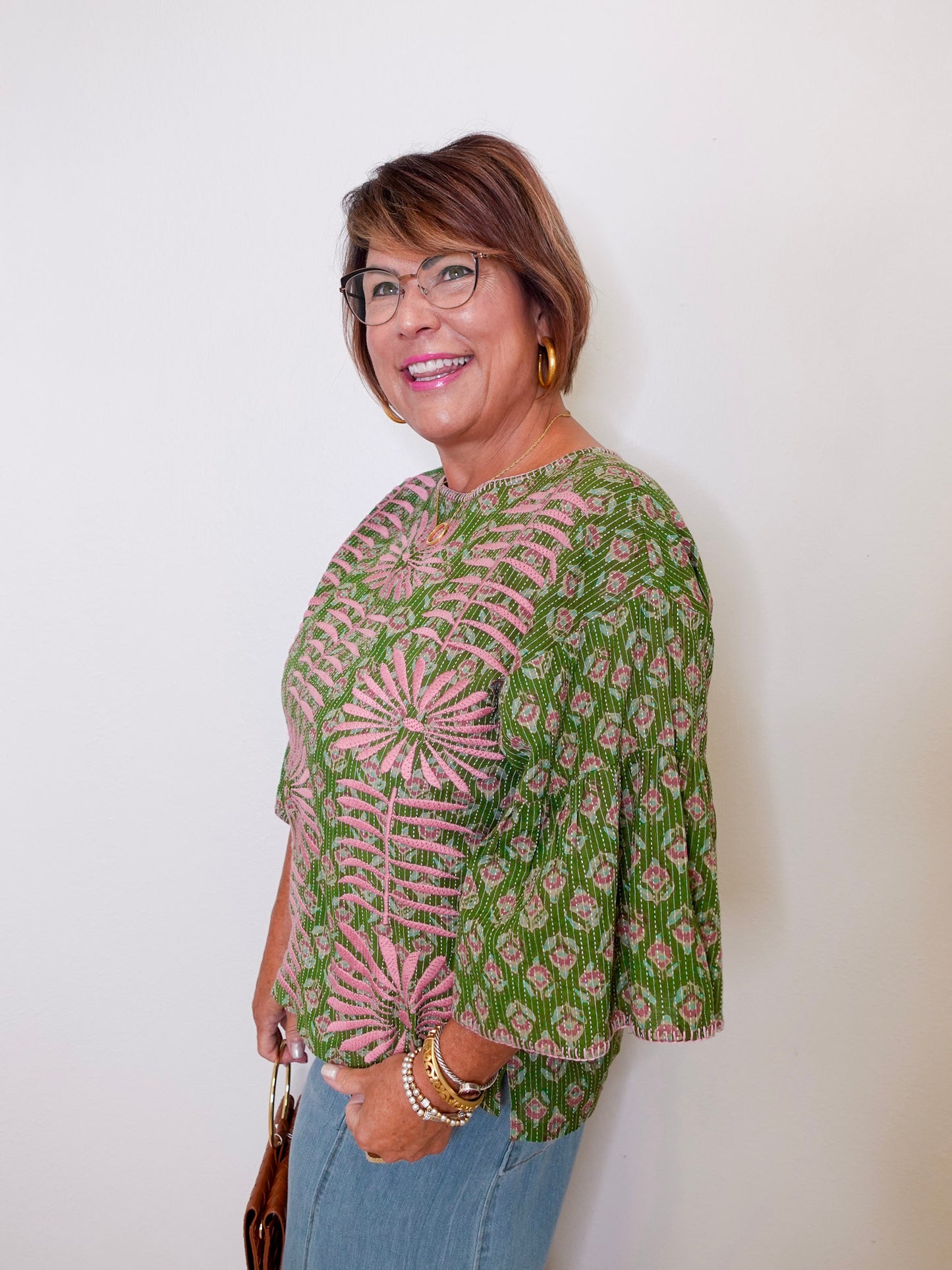 Woman wearing a green and pink patterned blouse against a white background