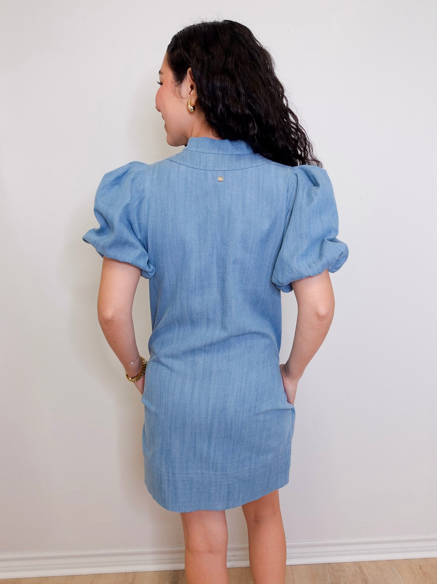 Woman wearing a blue denim dress against a white wall