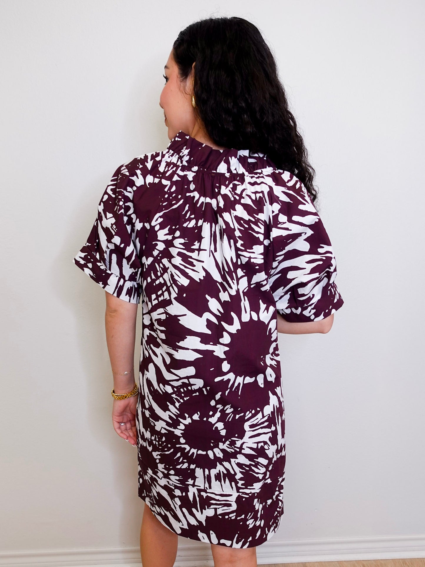 Woman wearing a patterned dress against a white wall