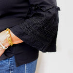 Close-up of a black sleeve with embroidered detailing on a white background