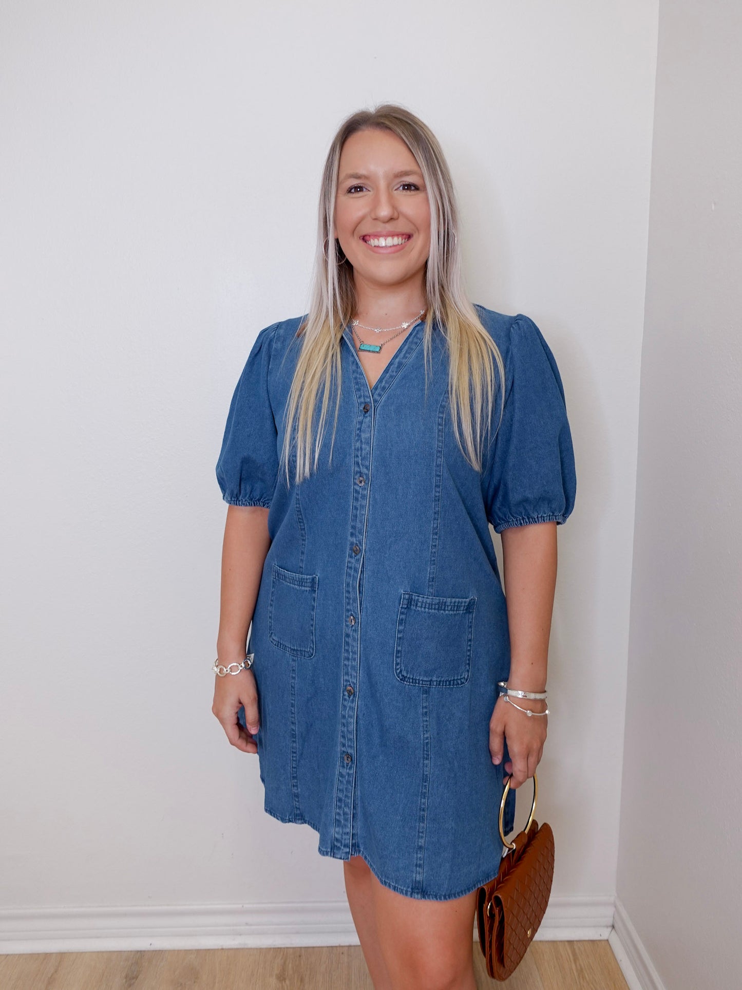 Woman wearing a blue denim dress against a white wall