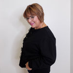 Woman wearing a black outfit with floral details against a plain background