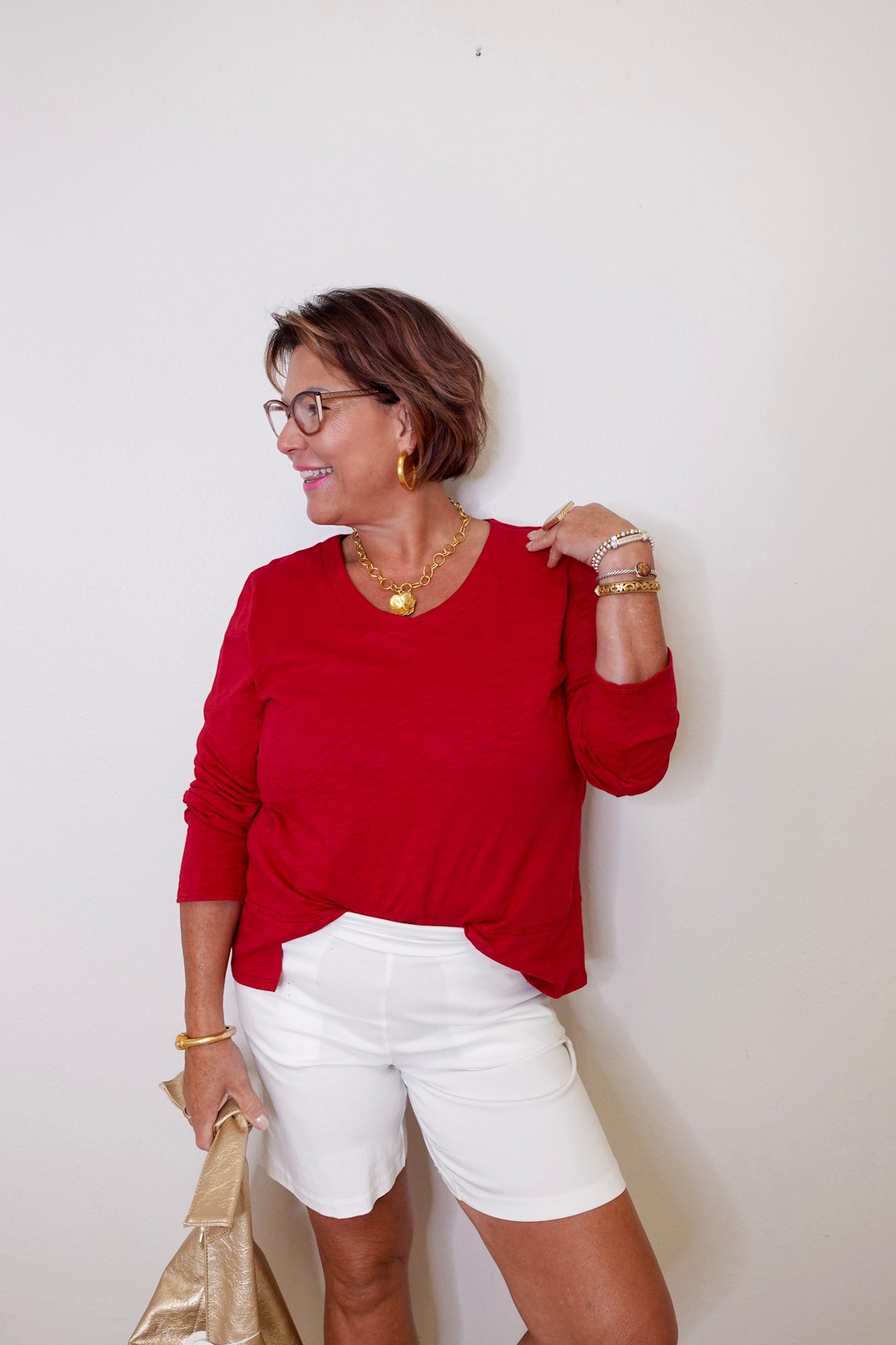Woman wearing a red top and white shorts against a plain background