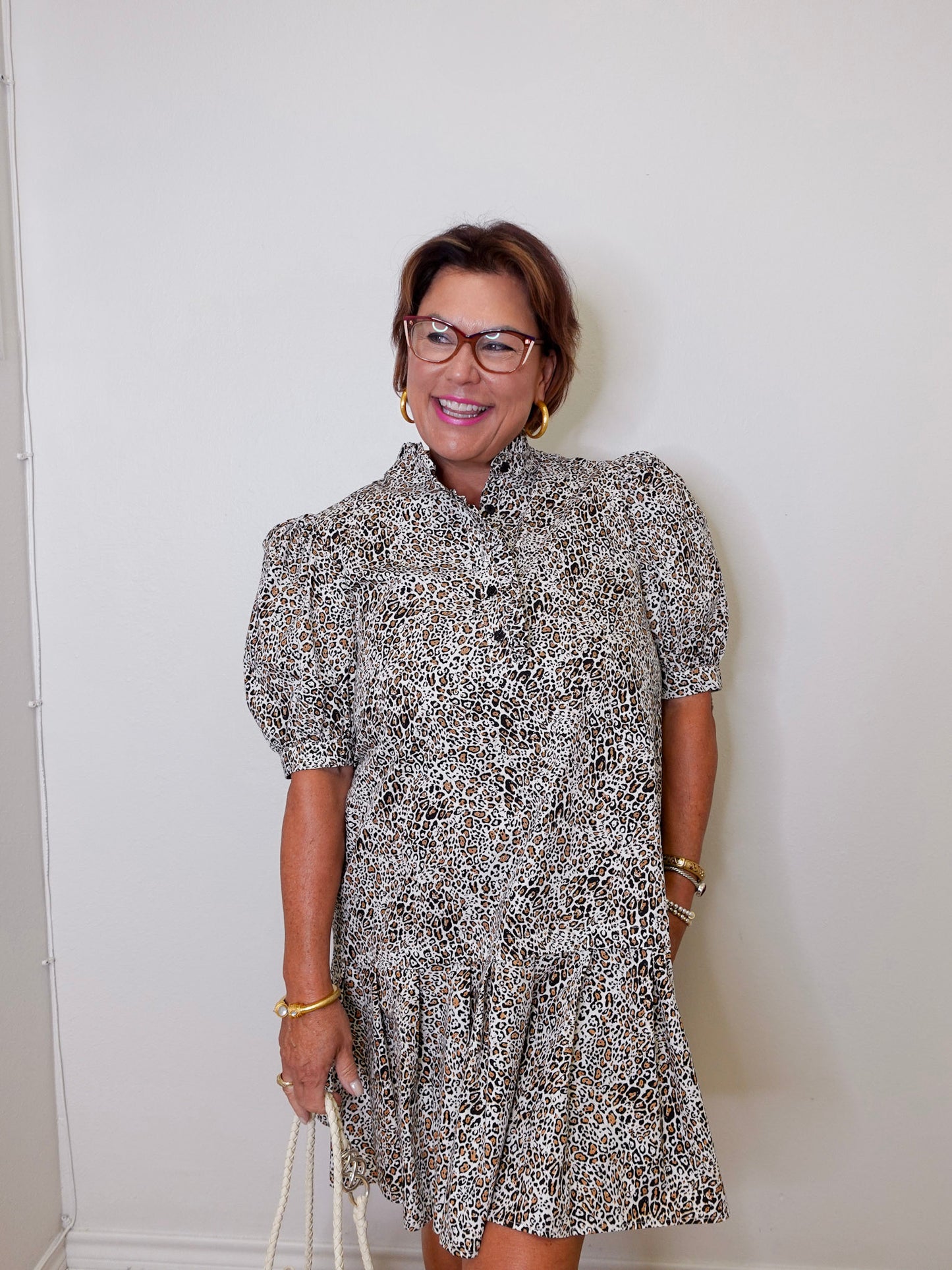 Woman wearing a patterned dress against a white wall