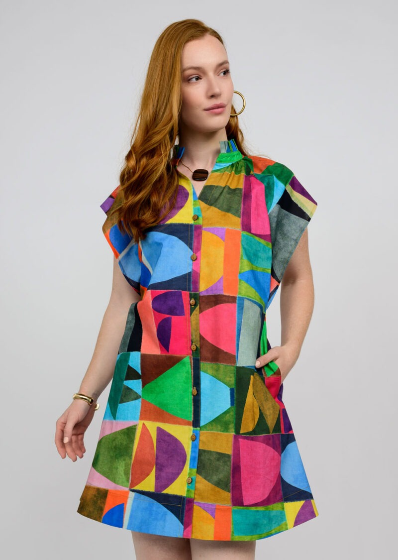 Woman wearing a colorful geometric patterned dress on a plain background