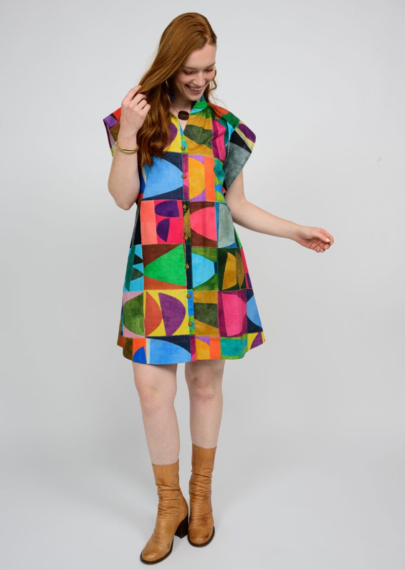 Woman wearing a colorful geometric patterned dress on a plain background