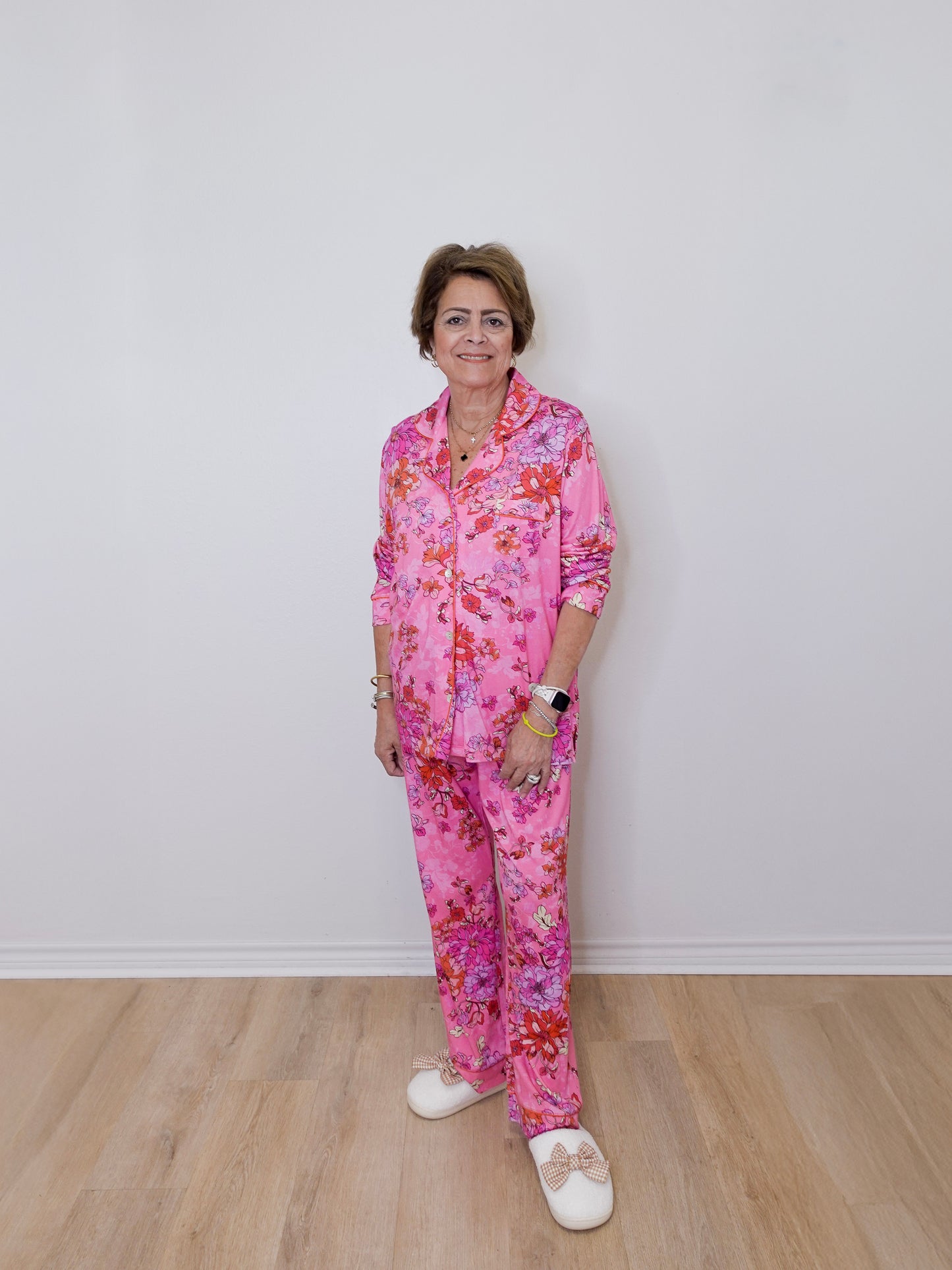 Person wearing a pink floral pajama set against a white wall.