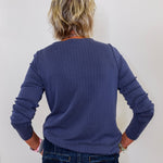 Person wearing a blue sweater and jeans against a white background