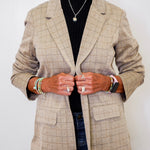Person wearing a beige checkered blazer with a plain background