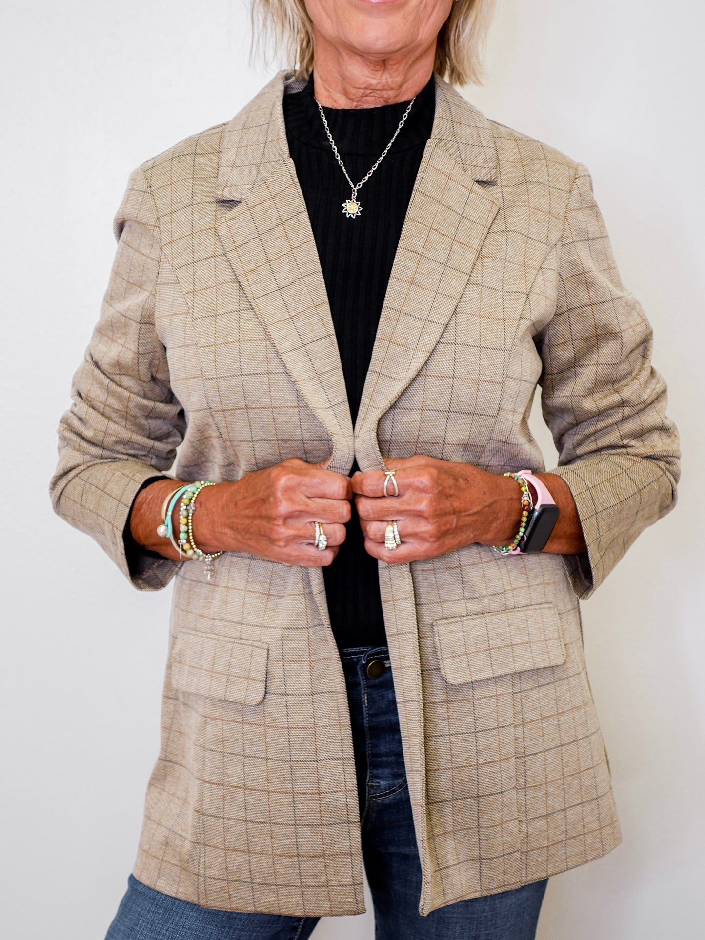 Person wearing a beige checkered blazer with a plain background