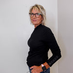 Person wearing a black sweater and glasses against a plain background