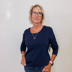 Woman wearing a navy top and jeans against a white background