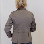 Person wearing a brown pinstripe jacket against a white background