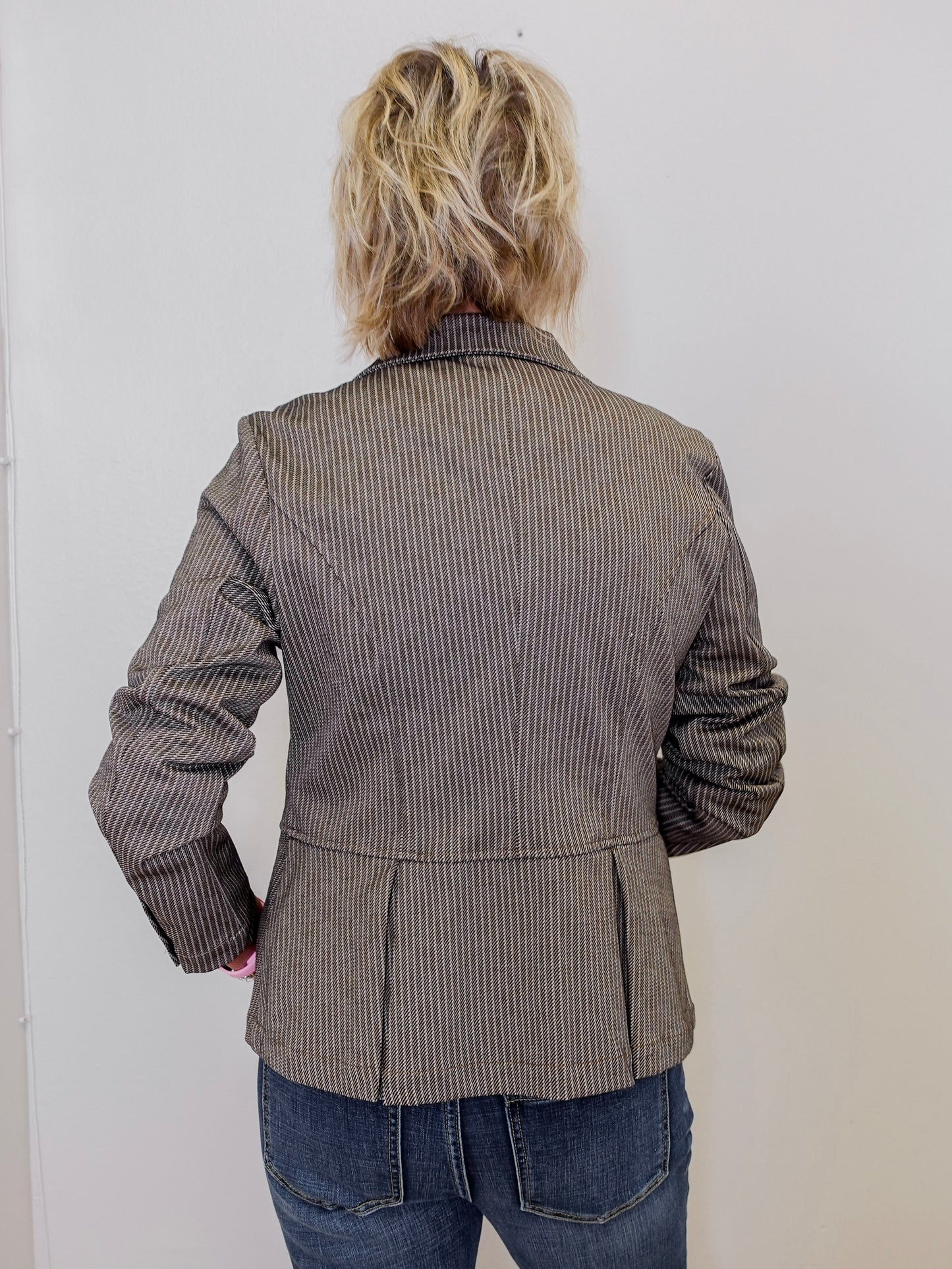 Person wearing a brown pinstripe jacket against a white background
