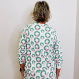 Person wearing a festive dress with wreath and bow pattern against a white background