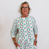 Person wearing a green and pink patterned outfit against a white background