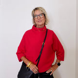 Woman wearing a red sweater and black pants against a white background