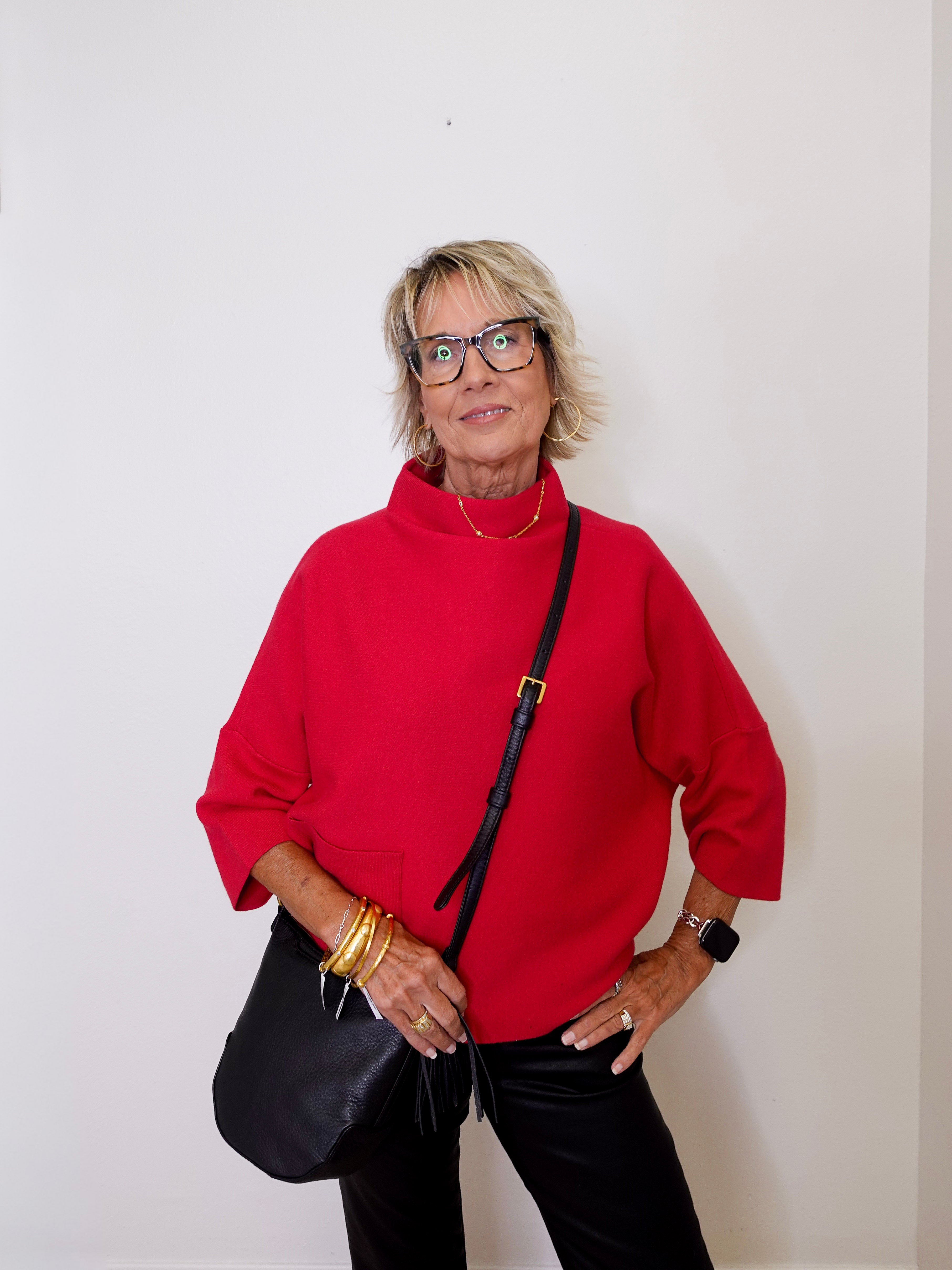 Woman wearing a red sweater and black pants against a white background