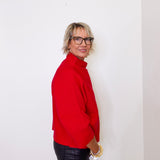Woman wearing a red sweater and black leather pants against a white background