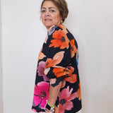 Woman wearing a colorful floral jacket against a white background