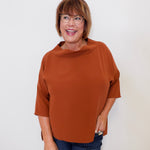 Woman wearing a brown top and glasses against a white background