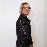 Person wearing a black tie-dye jacket against a white background