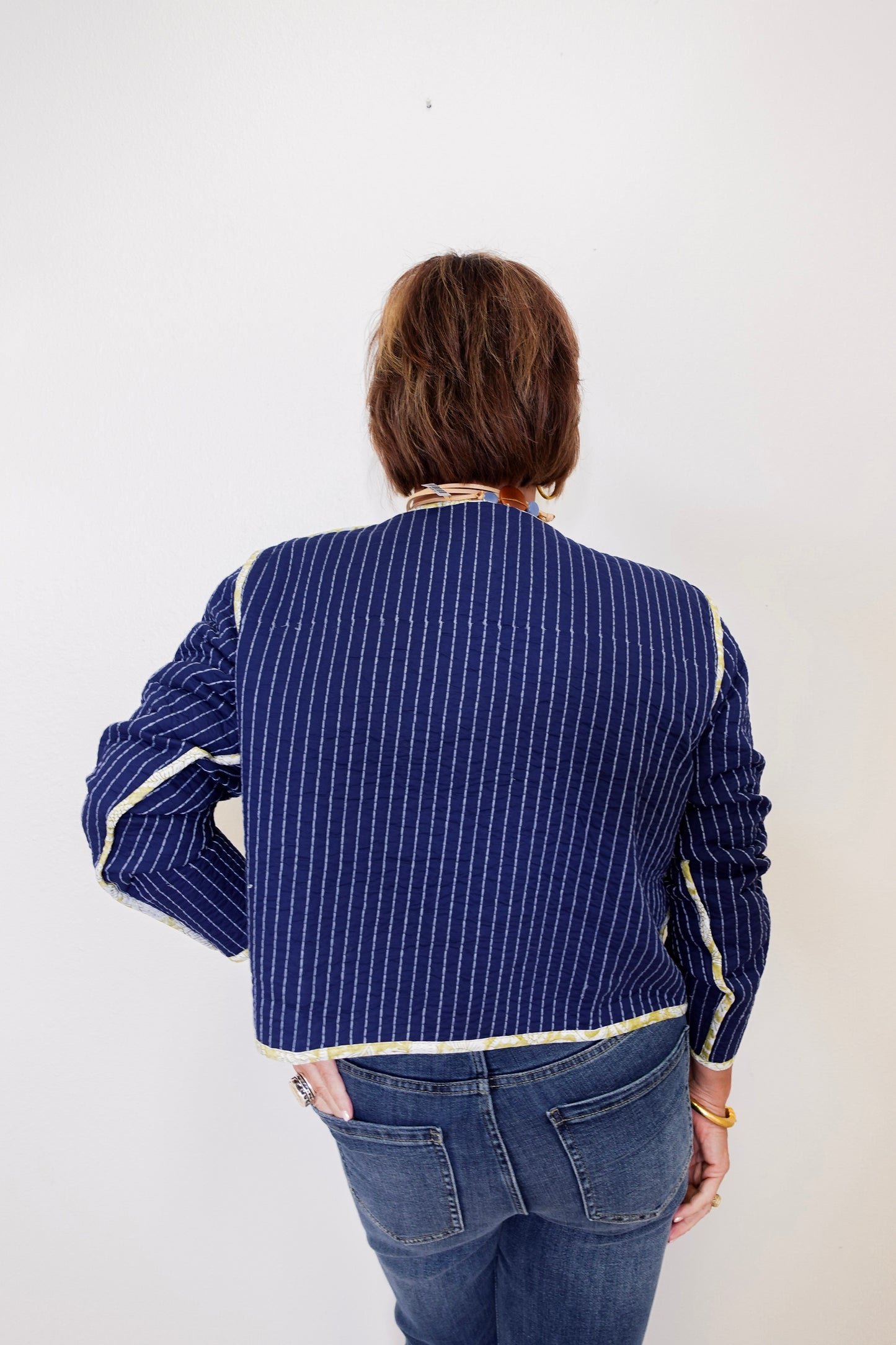 Person wearing a blue pinstripe shirt with white trim on a plain background