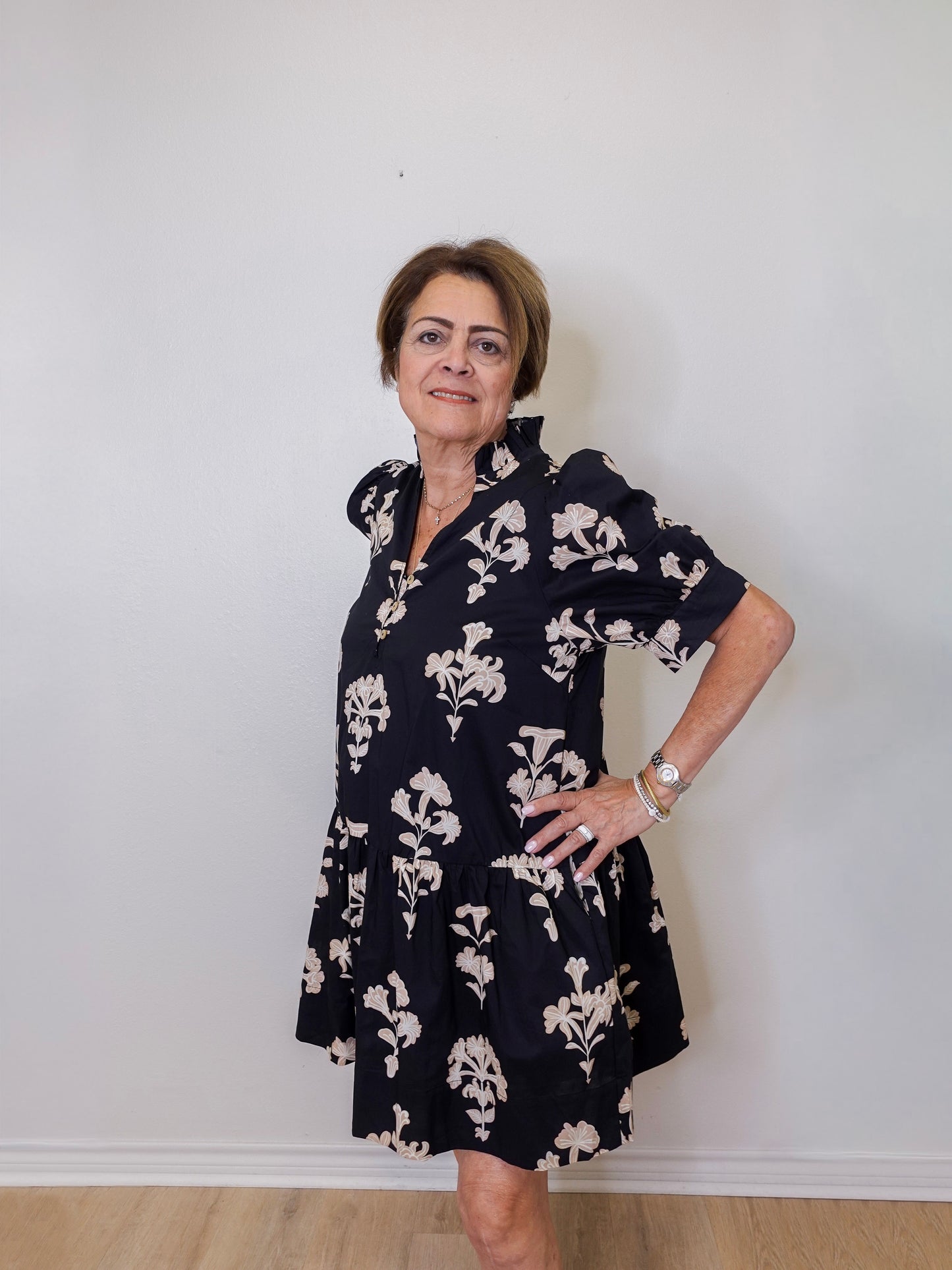 Woman wearing a navy floral dress against a white wall