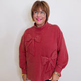 Woman wearing a red sweater with bow details against a white background
