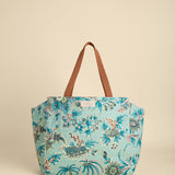 Floral-patterned tote bag with brown handle on beige background