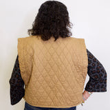 Person wearing a beige quilted vest with a white background