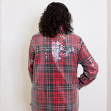 Person wearing a red and black plaid sequin jacket against a white background