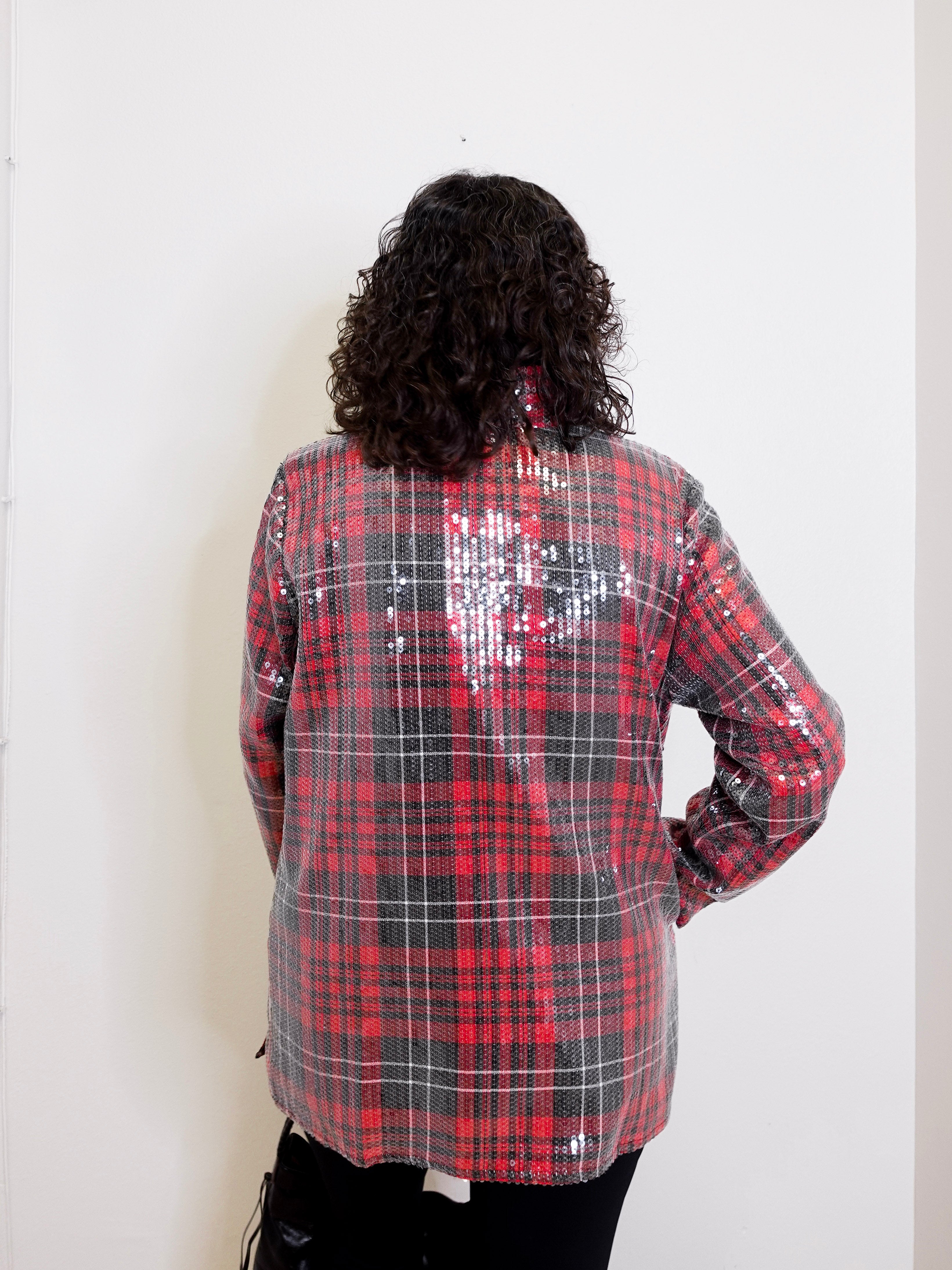 Person wearing a red and black plaid sequin jacket against a white background