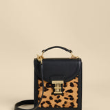 Small black handbag with a leopard print pocket on a beige background