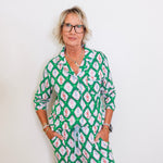 Woman wearing a green patterned outfit against a white background