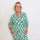 Woman wearing a green patterned outfit against a white background