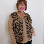Woman wearing a leopard print cardigan over a beige sweater against a white background