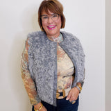 Woman wearing a gray fur vest over a patterned top against a white background