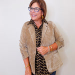 Woman wearing a beige blazer over a patterned shirt with a white background