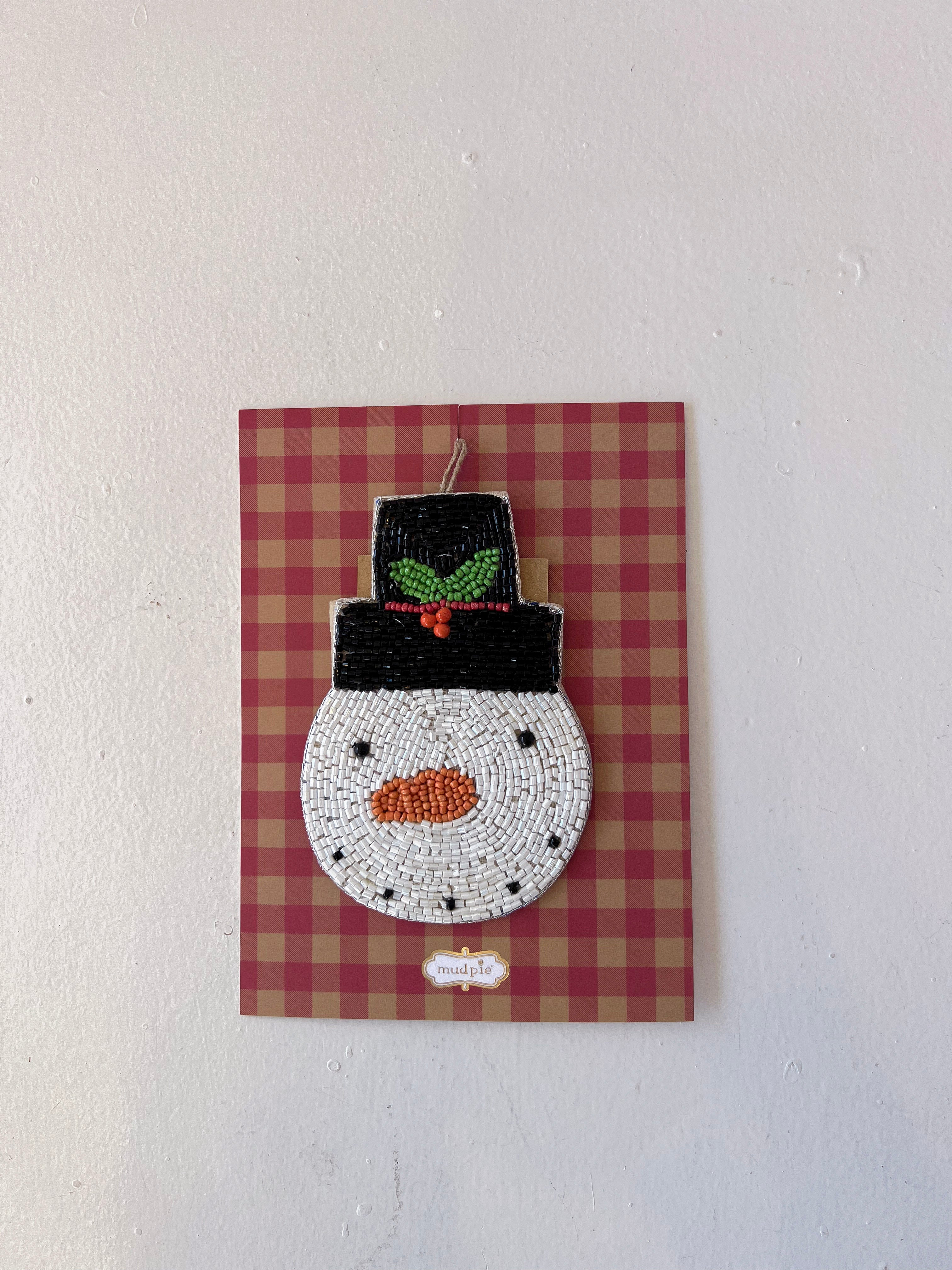 Decorative snowman ornament on a red and brown checkered background