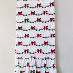 White towel with red bows and green dots pattern on a light gray background
